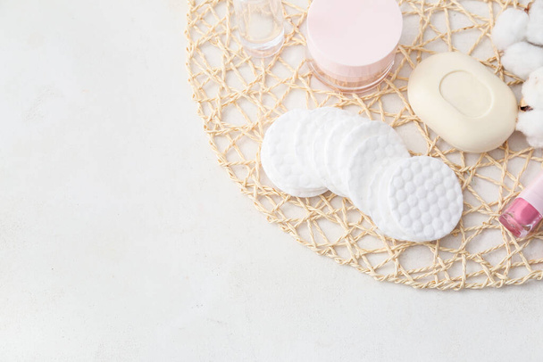 Tapis en osier avec tampons en coton propre et cosmétique sur fond blanc - Photo, image
