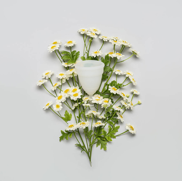 Copo menstrual com flores de camomila no fundo claro - Foto, Imagem