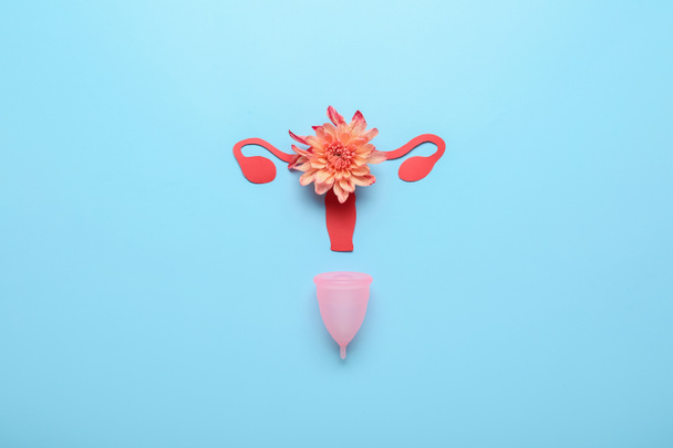Samenstelling met menstruatiecup en bloem op kleur achtergrond - Foto, afbeelding