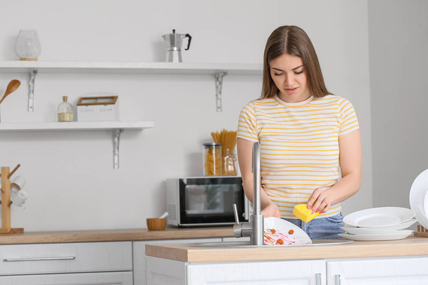 Junge Frau spült Geschirr in Küche - Foto, Bild