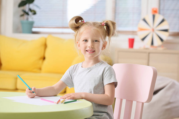 Cute little girl with ponytails drawing at table in living room - Foto, Imagem