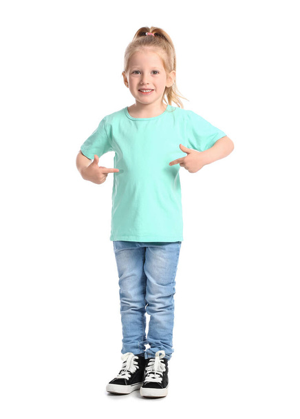 Little girl with ponytail pointing at blue t-shirt on white background - Fotoğraf, Görsel