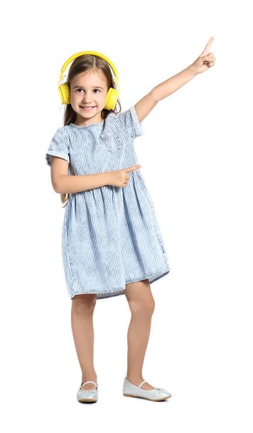 Cute little girl in yellow headphones dancing on white background - Photo, Image