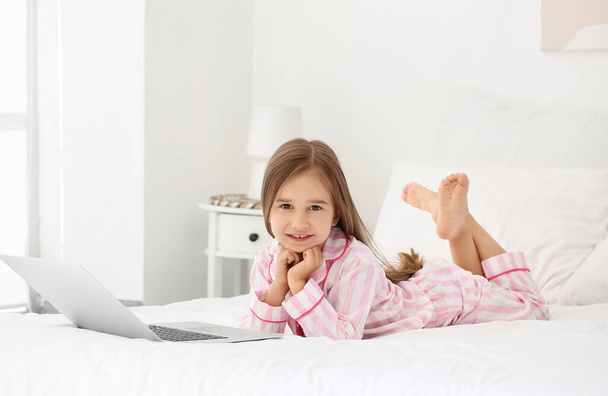 Cute little girl oglądanie kreskówek na laptopie w sypialni - Zdjęcie, obraz