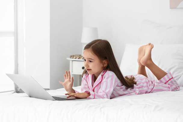 Мила дівчинка дивиться мультфільми на ноутбук у спальні
 - Фото, зображення