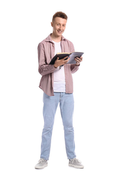 Young man reading Holy Bible on white background - Photo, Image
