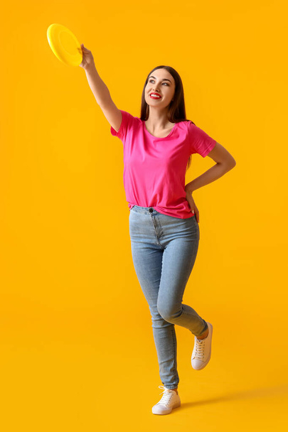 Beautiful young woman playing frisbee on color background - Fotoğraf, Görsel