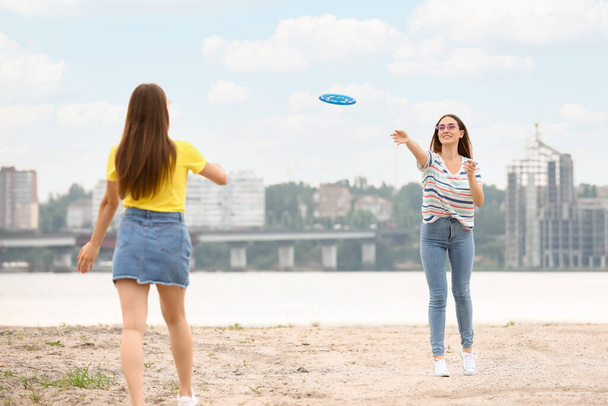 Jovens mulheres bonitas jogando frisbee perto do rio - Foto, Imagem