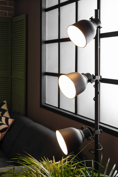 Glühende Stehlampe neben Fenster im dunklen Raum - Foto, Bild