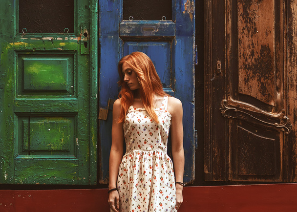 red-haired girl on the street outside wooden doors - Foto, Imagen