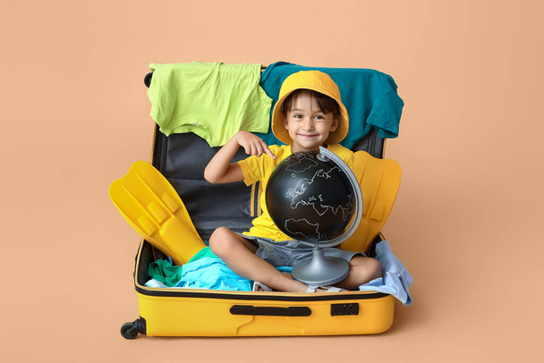 Kleiner Junge mit Globus und Koffer auf farbigem Hintergrund - Foto, Bild