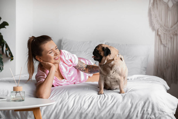 Молода жінка з милий мопс собака лежить на ліжку
 - Фото, зображення