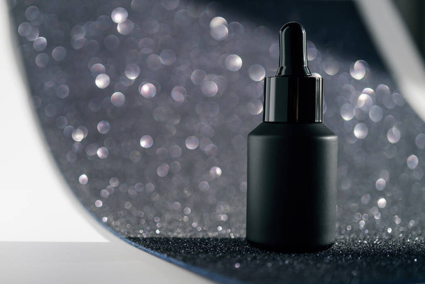 Black cosmetic bottles on a shining party background. - Valokuva, kuva