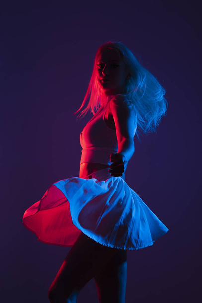 A portrait of a young Canadian woman in sportswear posing under blue and red lights in a dark studio - Photo, image