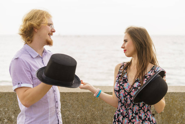 Vintage retro couple, man and woman outside wearing fedora hats by seaside. Girlfriend and boyfriend discussing - Photo, image