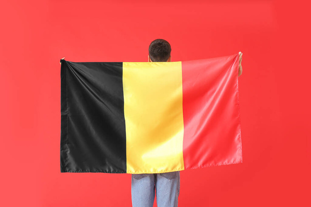 Młody człowiek z flagą Belgii na tle koloru - Zdjęcie, obraz