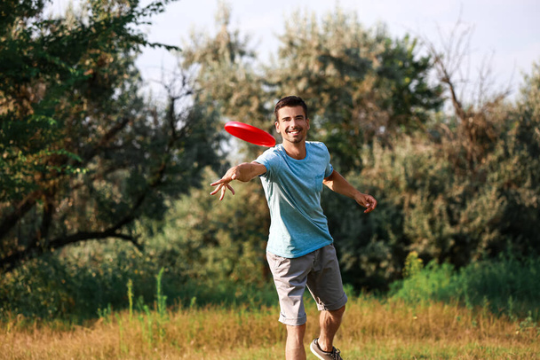 Young man throwing frisbee in park - Fotoğraf, Görsel