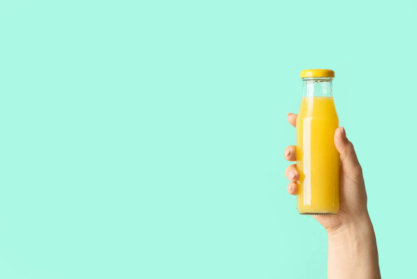 Female hand with bottle of healthy juice on color background - Photo, Image
