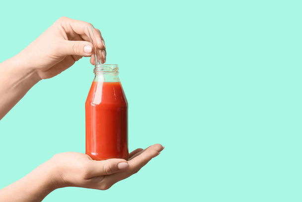 Female hands with bottle of healthy juice on color background - Fotó, kép