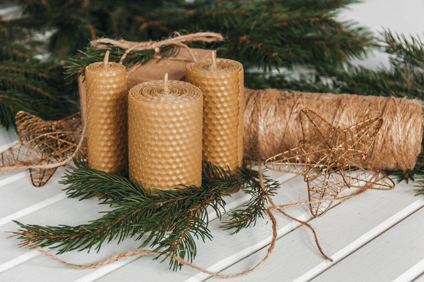 Bougies en nid d'abeille près de la décoration de l'arbre de Noël sur fond blanc - Photo, image