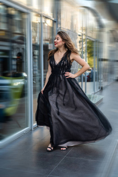 Fashion young woman full length in evening black dress walking in city daytime. Street style - Φωτογραφία, εικόνα