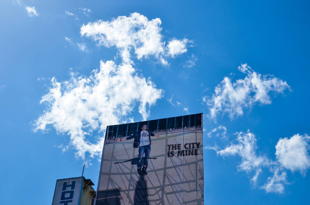 2012年4月16日-インド・シロン:青い曇り空に対してホテルの屋上に大規模な広告看板。大きな広告バナーとホテルのテラスでのプロモーションキャンペーン。浮かんでいる雲と青空と街の風景 - 写真・画像