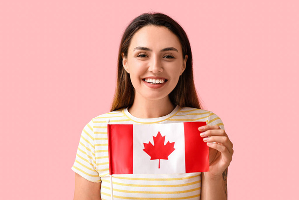 Όμορφη νεαρή γυναίκα με σημαία του Καναδά στο φόντο χρώμα - Φωτογραφία, εικόνα