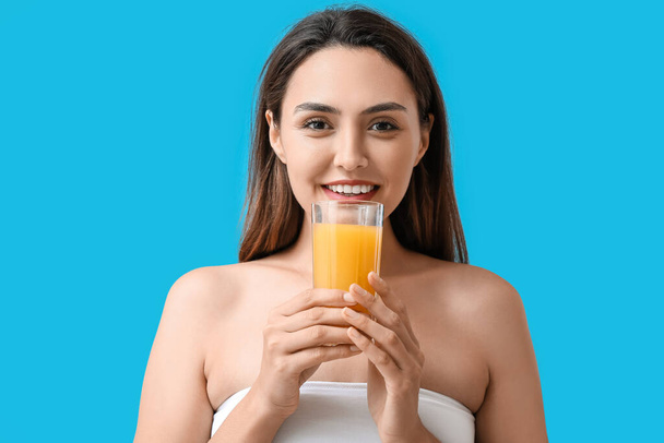 Young woman with glass of orange juice on color background - Фото, изображение