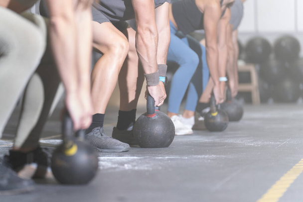 Grupo de atletas sin rostro haciendo ejercicio con pesas en un centro de entrenamiento cruzado - Foto, Imagen