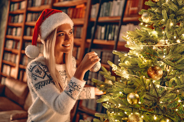 Karácsonyi nő. Boldog karácsonyt és boldog ünnepeket! Boldog lány díszíteni a karácsonyfát beltérben - mágia karácsonyi bokeh. Karácsony előtti reggelen. Portré szerető szőke lány közelről - Fotó, kép