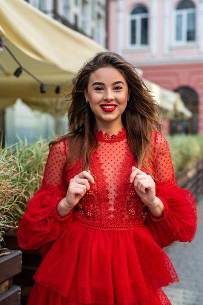красива стильна брюнетка позує в червоній сукні на міському фоні
 - Фото, зображення