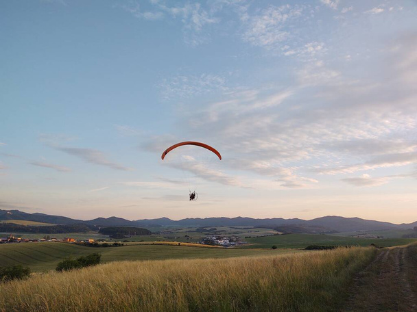 Gleitschirm fliegt am Himmel vor Naturkulisse - Foto, Bild