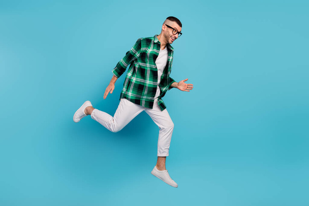 Full length photo of happy positive cheerful man jump up run empty space hurry sale isolated on blue color background - Valokuva, kuva