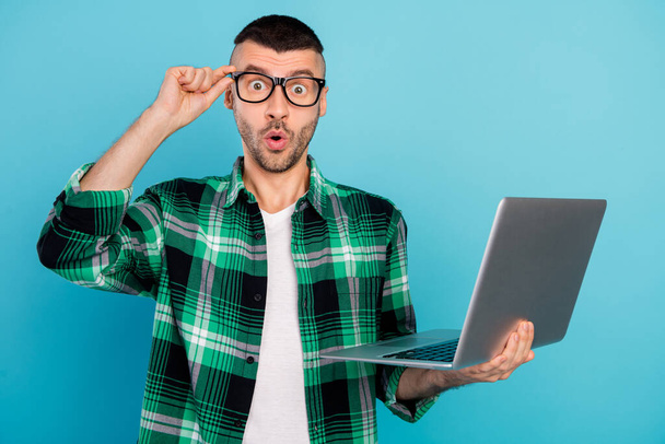 Photo of amazed shocked man hold computer wear glasses astonished face isolated on blue color background - Foto, Imagem