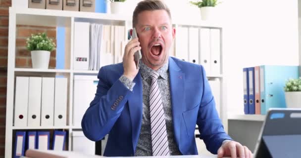 Jovem empresário grita em smartphone no local de trabalho filme 4k - Filmagem, Vídeo