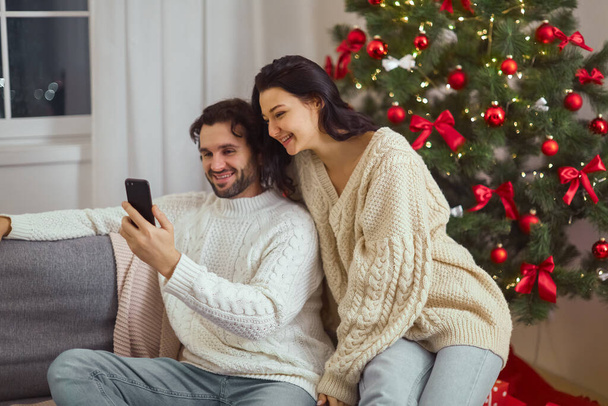 Couple Celebration New Year Near Christmas Tree at Home, Video Call or Selfie on Smartphone - Valokuva, kuva