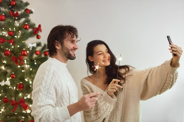 Couple Celebration New Year Near Christmas Tree at Home, Video Call or Selfie on Smartphone - Foto, Imagen