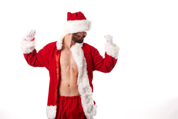 Άγιος Βασίλης bodybuilder αναδεικνύει το αθλητικό σώμα του σε λευκό φόντο - Φωτογραφία, εικόνα