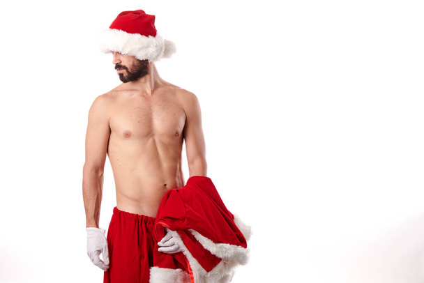 Père Noël bodybuilder montrant son corps athlétique sur un fond blanc - Photo, image