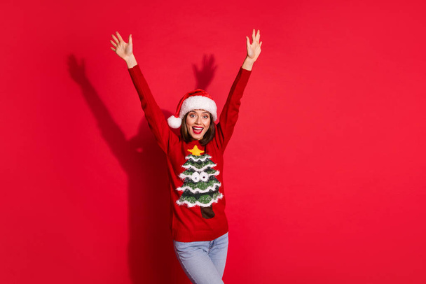 Photo of funky impressed young lady dressed print pullover celebrating new year rising arms isolated red color background - Fotoğraf, Görsel