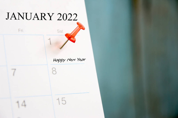 Κόκκινη καρφίτσα την 1η της πρώτης ημέρας του έτους 2022 στο ημερολόγιο. - Φωτογραφία, εικόνα
