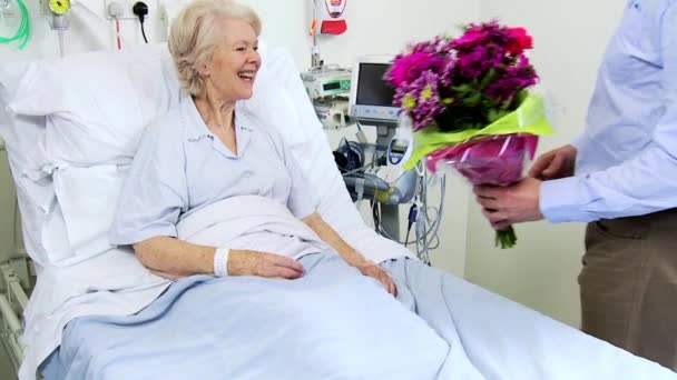 starszy pacjent jest odwiedzana przez syna z kwiatami - Materiał filmowy, wideo