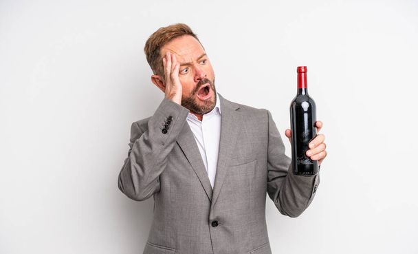 middle age handsome man feeling happy, excited and surprised. wine bottle concept - Foto, immagini
