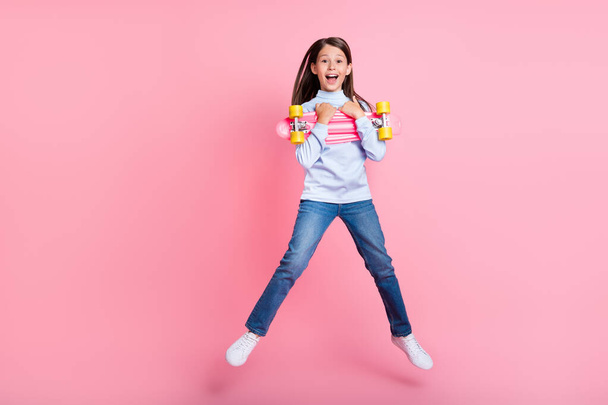 Full length body size view of pretty cheerful girl jumping hugging skate having fun isolated over pink color background - Fotografie, Obrázek