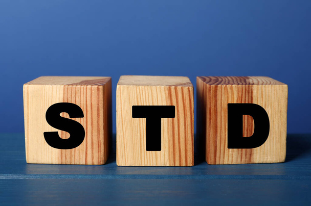 Wooden cubes with letters STD (sexually transmitted diseases) on blue table - Photo, Image