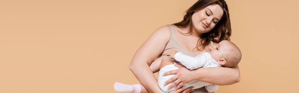 Happy plus size mother looking at daughter isolated on beige, banner  - Foto, Imagem