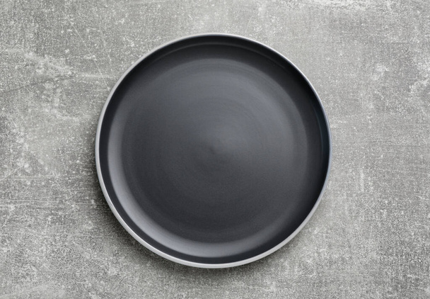 New dark plate on light grey table, top view - Foto, Imagen