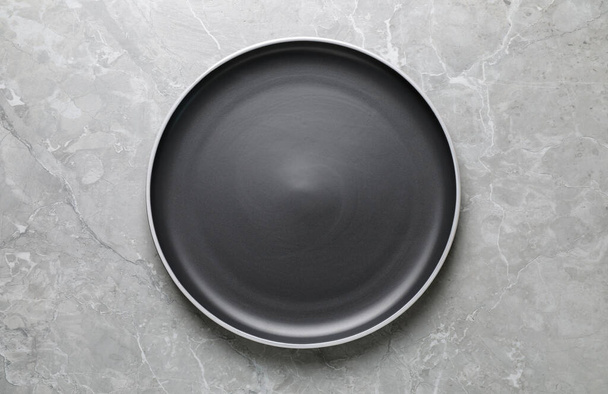 New dark plate on light grey marble table, top view - Foto, immagini