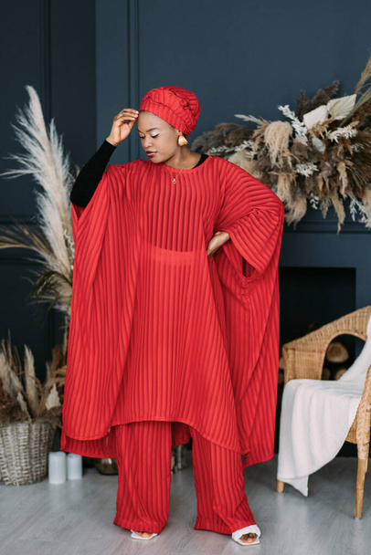 Attractive African-american fashion woman in red suit and headscarf in modern studio - 写真・画像