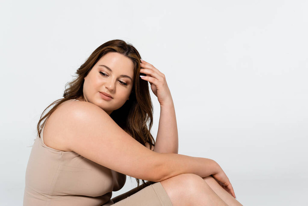 Junge brünette Frau mit Übergewicht schaut isoliert von grau weg - Foto, Bild